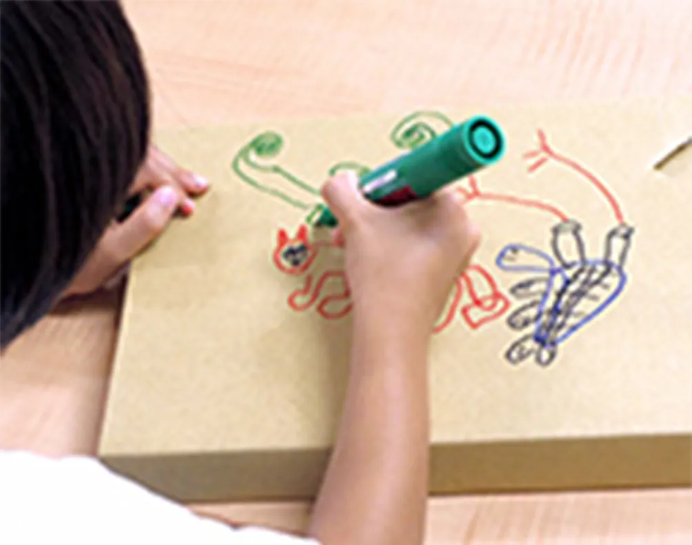 Student drawing on corrugated cardboard